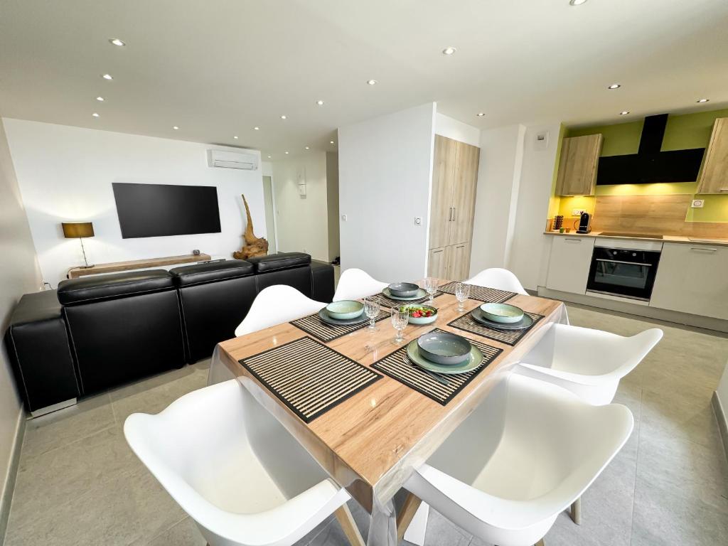 une salle à manger avec une table en bois et des chaises blanches dans l'établissement La SébaïaVie, à Sète