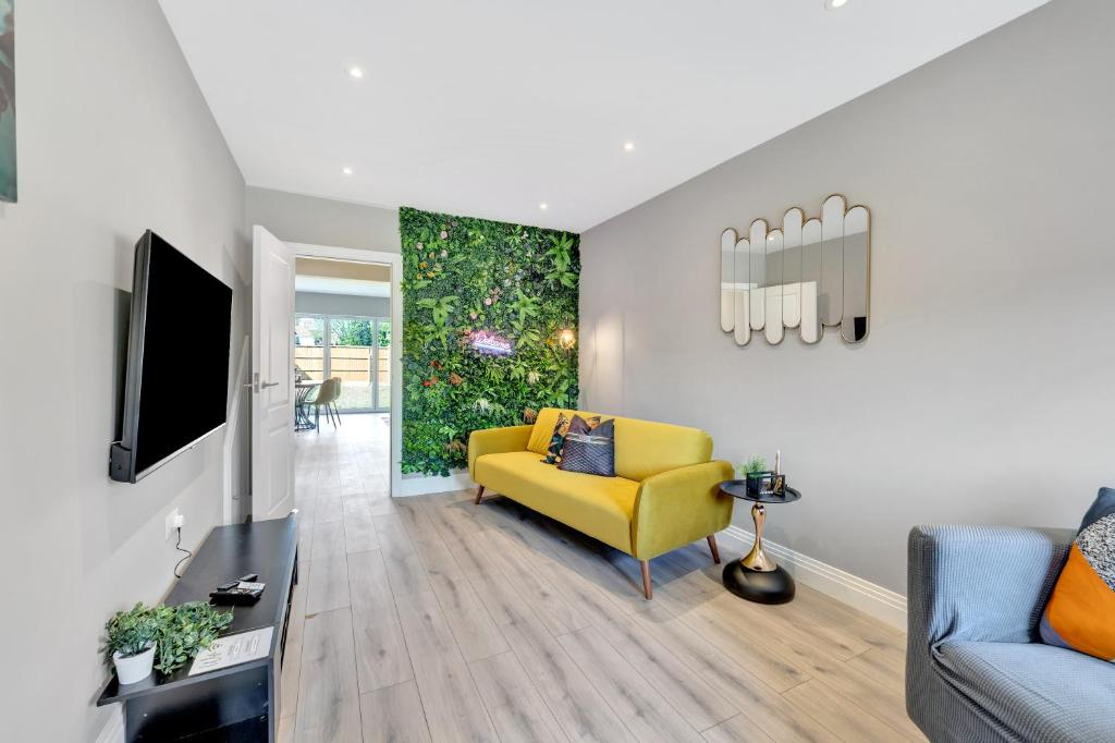 a living room with a yellow couch and a tv at Travard at Heathrow 386a in Harmondsworth