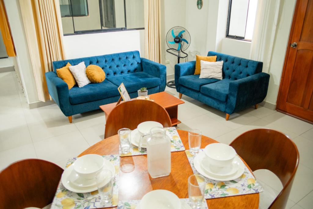 a living room with blue couches and a table and chairs at El Hogar de Olguita - Departamento Deluxe in Tarapoto