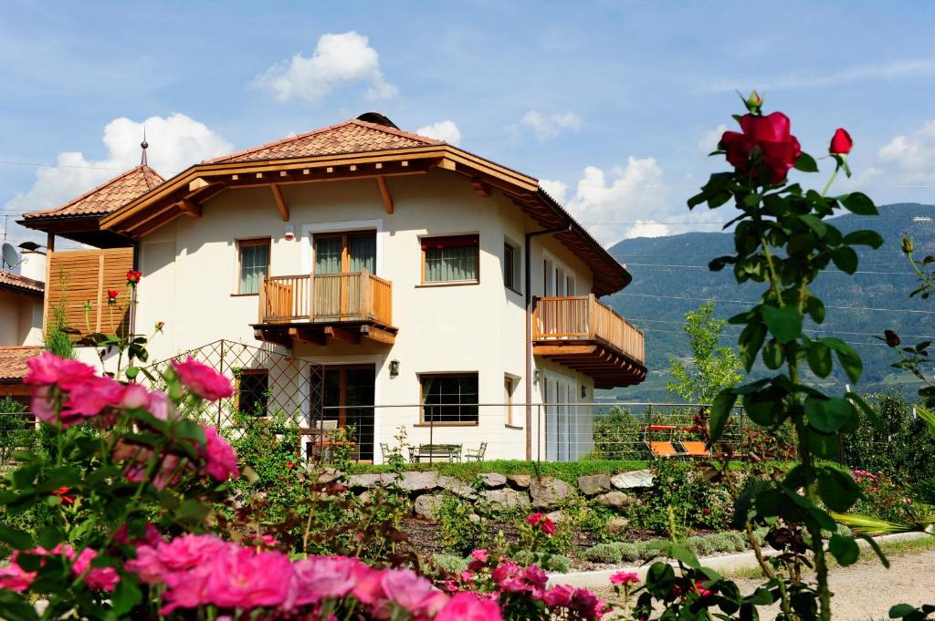 ein weißes Haus mit einem Balkon und rosa Blumen in der Unterkunft Ansitz Waldner Oberwirt in Marling