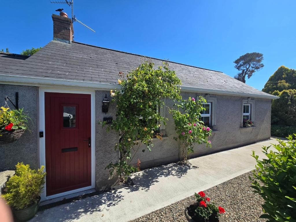 ein kleines Haus mit einer roten Tür und Blumen in der Unterkunft Newly Renovated Country Cottage in Portadown