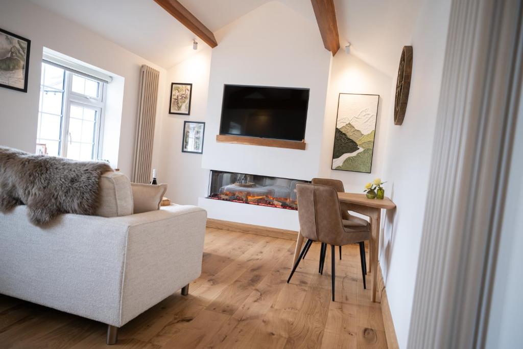 ein Wohnzimmer mit einer Couch, einem Tisch und einem Kamin in der Unterkunft Tucked Away in Keswick