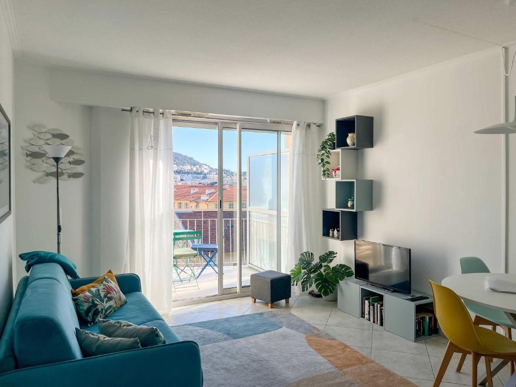 - un salon avec un canapé bleu et une porte coulissante en verre dans l'établissement Risso - charming one bedroom with a balcony, à Nice