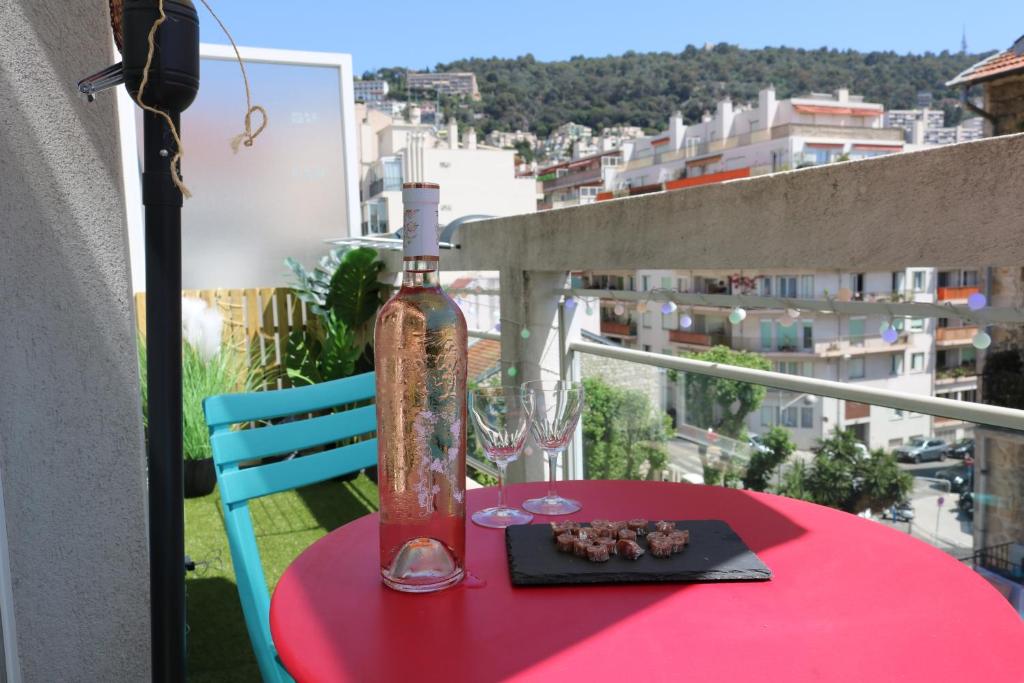 une table rouge avec une bouteille sur un balcon dans l'établissement Charmant studio climatisé avec terrasse ensoleillée, à Nice