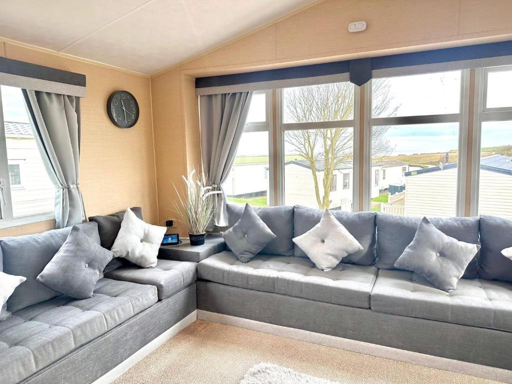 a living room with a large couch with pillows at 3 Bedroom 8 birth Caravan - Sand Le Mere in Tunstall