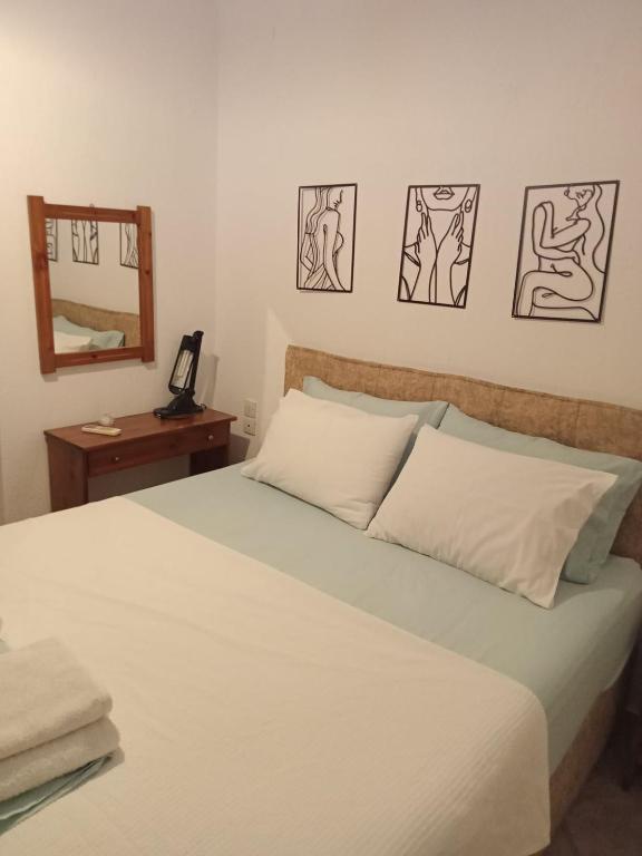 a bedroom with a large white bed with a mirror at Mantemi house in Skopelos Town