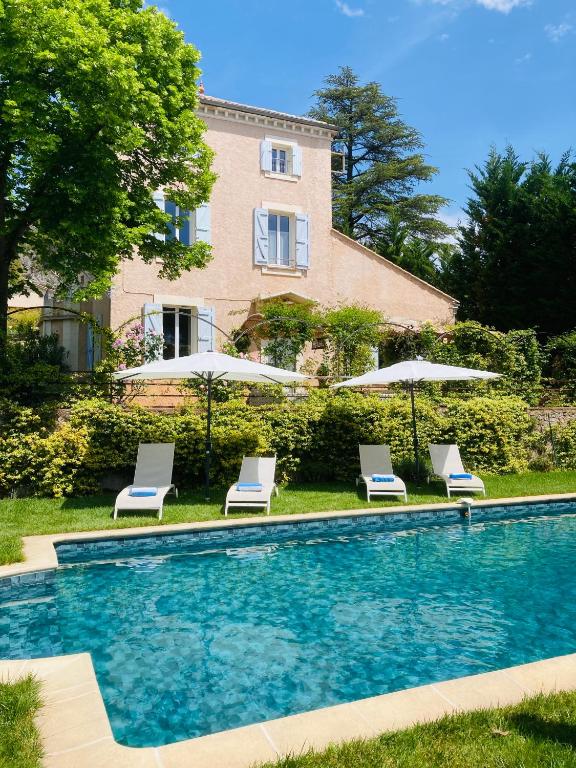 une piscine avec chaises et parasols à côté d'un bâtiment dans l'établissement La Bastide de Villecroze, à Villecroze