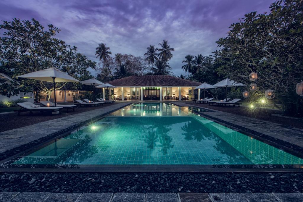 a swimming pool in front of a villa at night at Nyne Hotels - Rock Villa, Bentota in Bentota