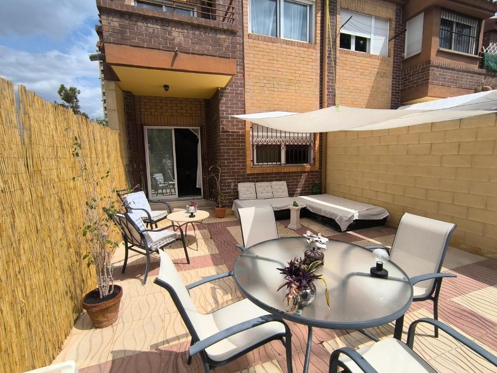 Un patio con una mesa de cristal y sillas. en Habitación Cabo Huertas, en Alicante