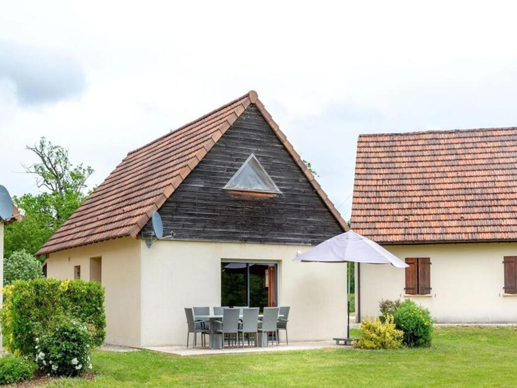 une maison avec une table, des chaises et un parasol dans l'établissement Lac Bleu Nr 38, à Lacapelle-Marival