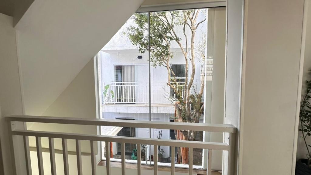 a balcony with a large window and a tree at Cantinho da Paz in Sao Paulo