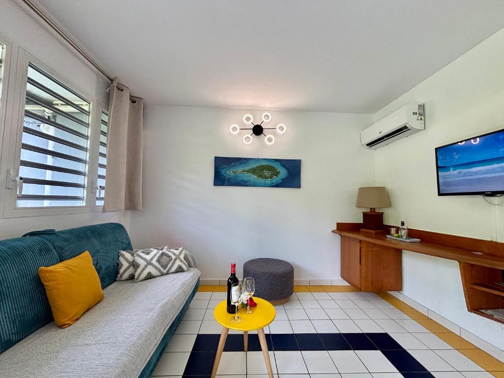 una sala de estar con un sofá y una mesa en Le Cocon Miel - Plage, Jardin, Adapté aux Groupes, en Folle Anse