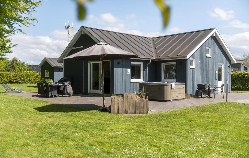 a small blue house with an umbrella in a yard at 3 Bedroom Nice Home In Hemmet in Hemmet