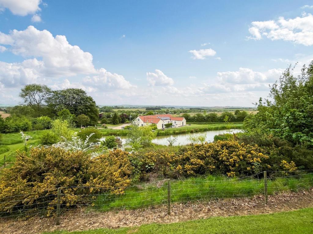 una casa in mezzo a un campo con un fiume di Katies Corner - Uk49741 a Fulletby