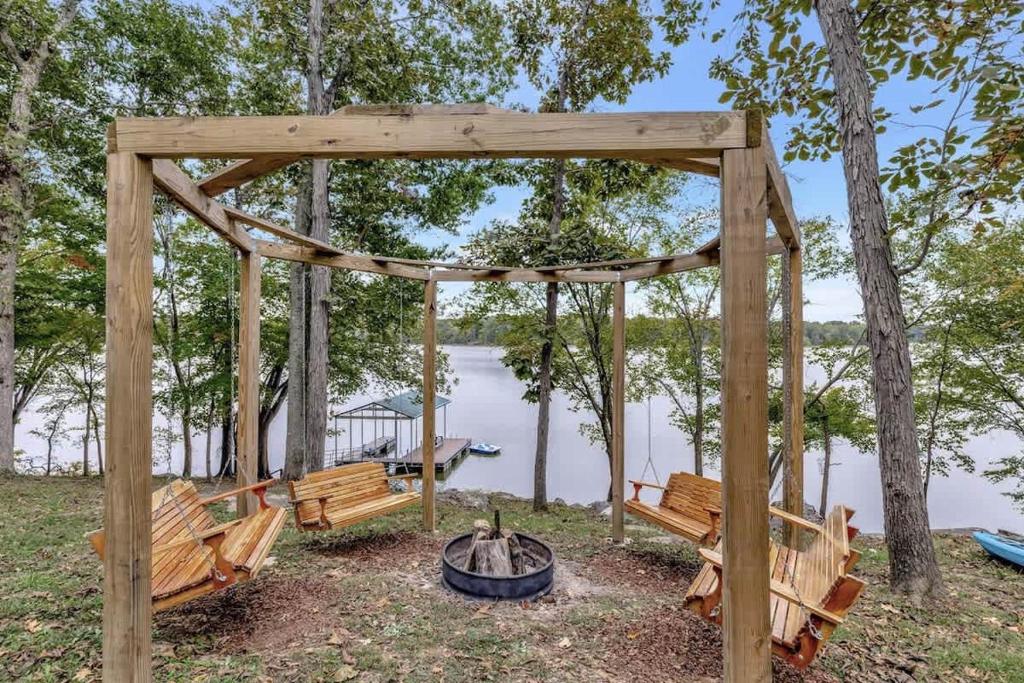 a wooden gazebo with benches next to a lake at Hickory Haven Cozy Lakefront Escape & Dock in Cadiz