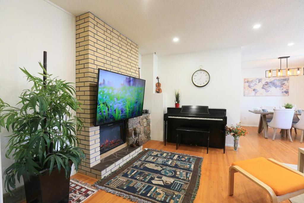 ein Wohnzimmer mit Kamin, Fernseher und Klavier in der Unterkunft Rocky Mtn Escape-3 bdrm-near shops, dining, UofC in Calgary