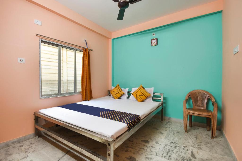 a bedroom with a bed and a window and a chair at SPOT ON Hotel O Maa Rakhakali Bhawan in Sāntrāgāchi