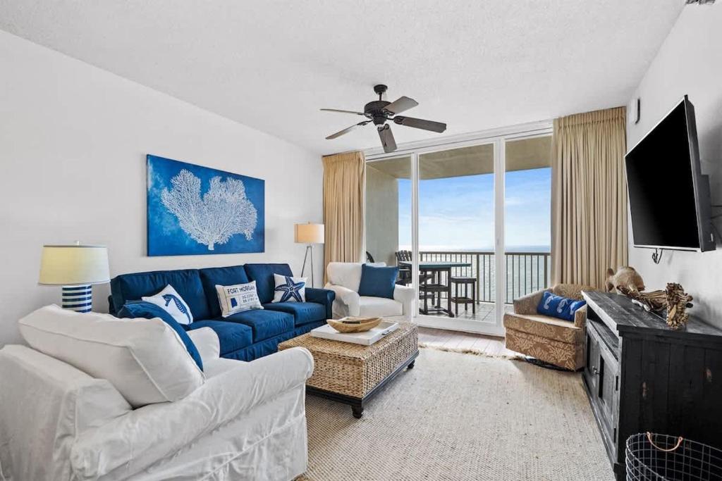 a living room with a blue couch and a tv at Pool & Spa - Beachfront - Golf - King Bed in Gulf Highlands