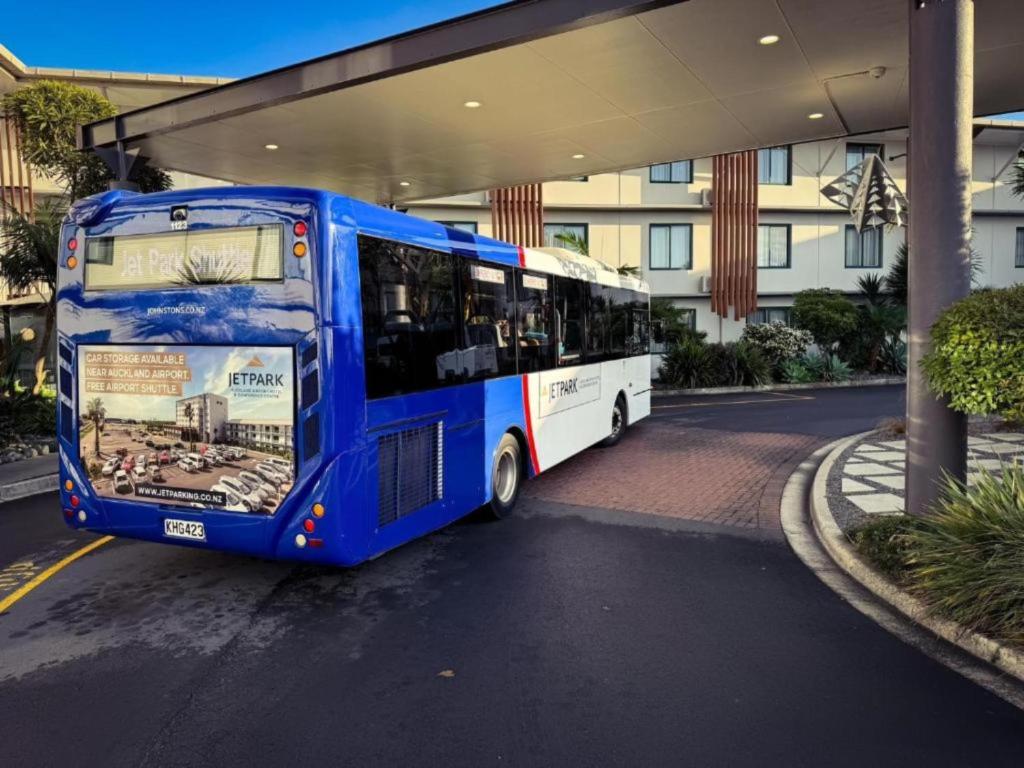 a blue bus parked in front of a building at JetPark Auckland Airport Hotel in Auckland
