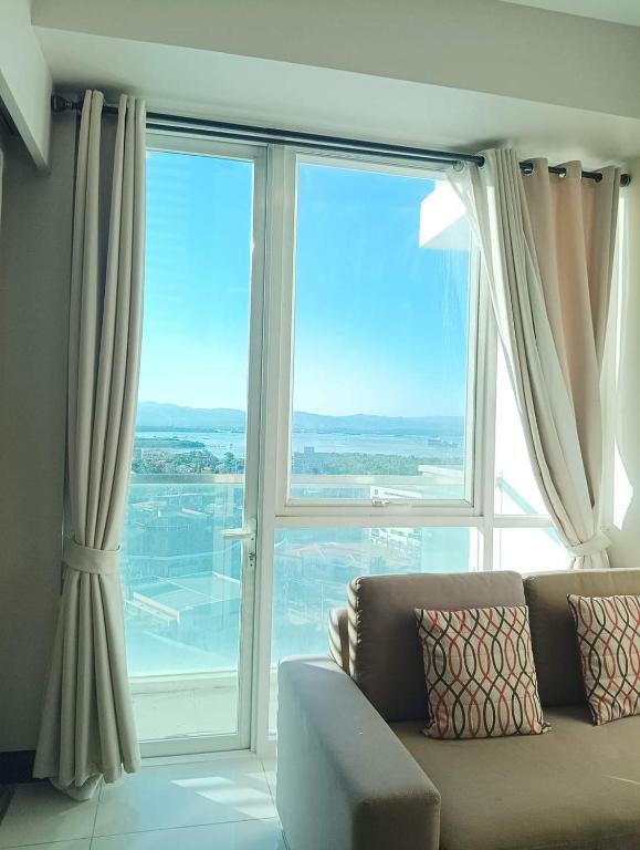 a living room with a couch and a large window at Mactan Newtown Beach Condo in Lapu Lapu City