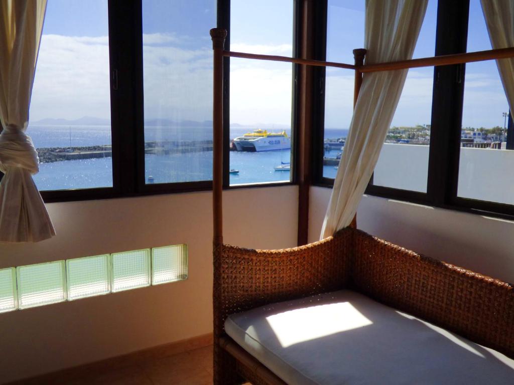 a room with windows with a bench and a boat in the water at Casa Bonica in Playa Blanca