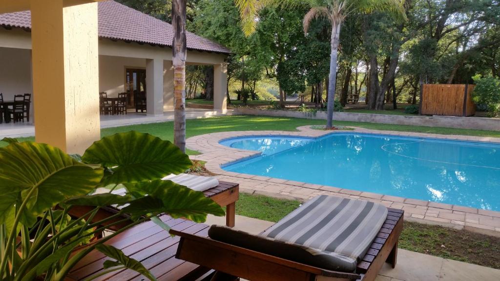 a swimming pool with a chaise lounge and a house at Summerset Place Country House in Bela-Bela