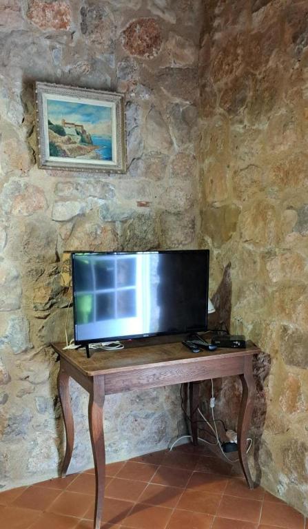 un écran d'ordinateur sur une table en bois dans un mur en pierre dans l'établissement Le gite le pigeonnier, à Fox-Amphoux