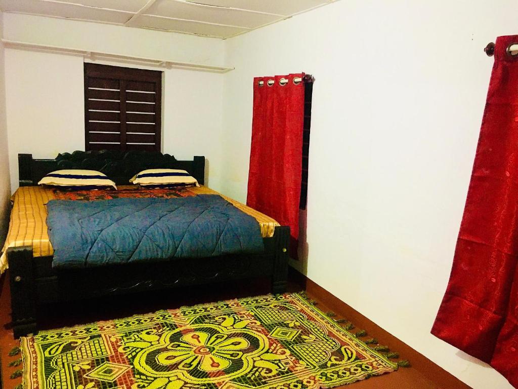 a bedroom with a bed with red curtains and a rug at Vintage Breeze Home Stay in Madikeri
