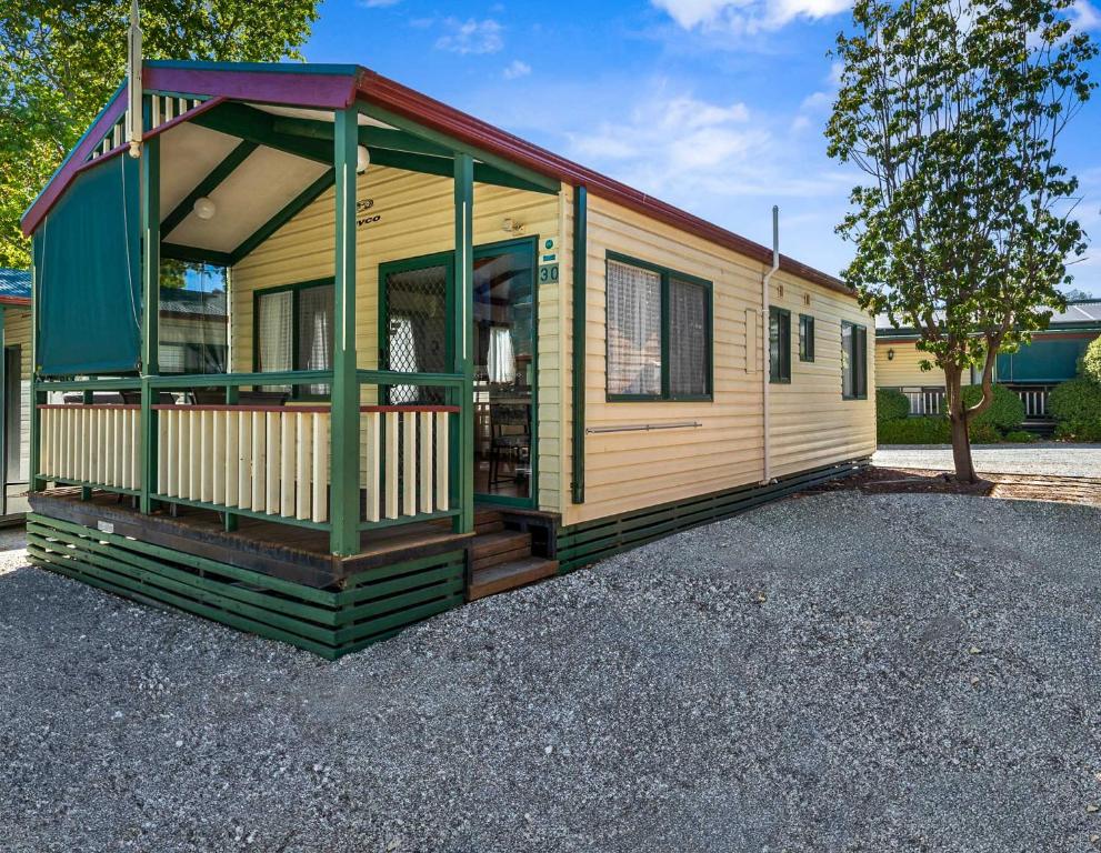 a yellow tiny house sitting on a gravel lot at Albury Holiday Park in Albury