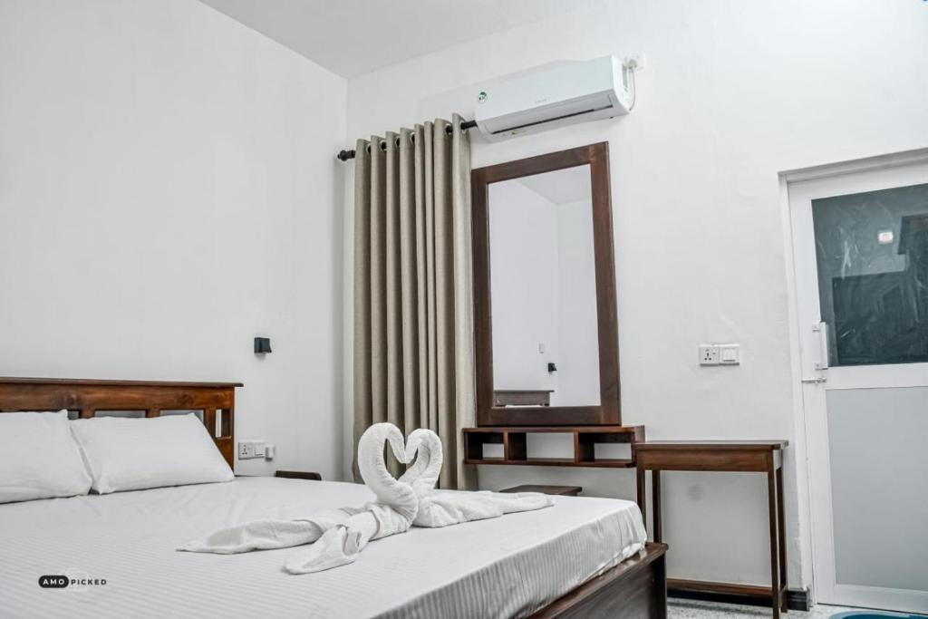 a bedroom with a bed with a towel in the shape of a heart at Coconut Resort Arugambay in Arugam Bay