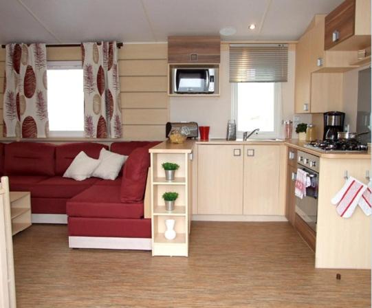 a living room with a red couch in a kitchen at Mobil Home in Saint-Jean-de-Monts