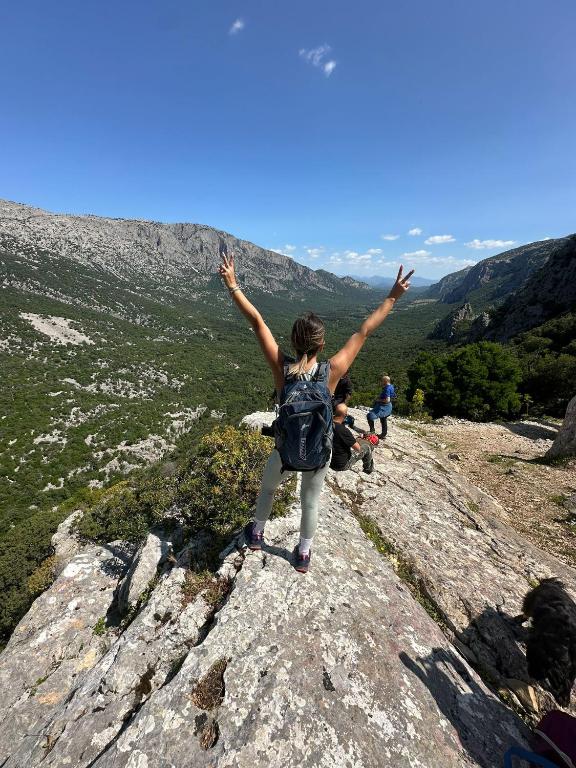 una donna in piedi su una roccia con le braccia alzate di EL MATORRAL ad Alghero