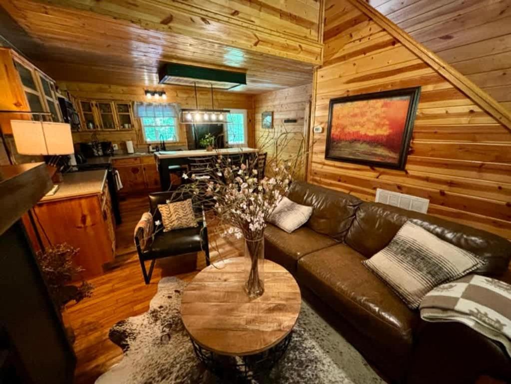 un soggiorno con un divano in pelle e un tavolo di Creekside with views - jacuzzi firepit arcade a Cosby