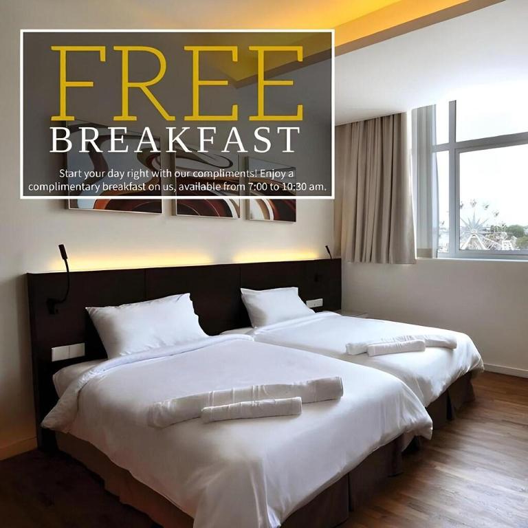 two beds in a hotel room with a free breakfast advertisement at MIO BOUTIQUE Hotel in Malacca