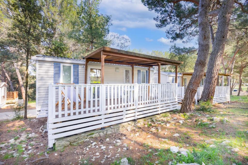 a tiny house with a white fence and a tree at Mobile homes Pine Sea Banjole in Banjole