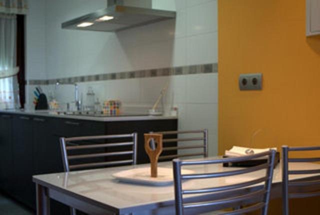 a kitchen with a table and chairs with a spoon on it at Apartamentos Tajamar in Lastres