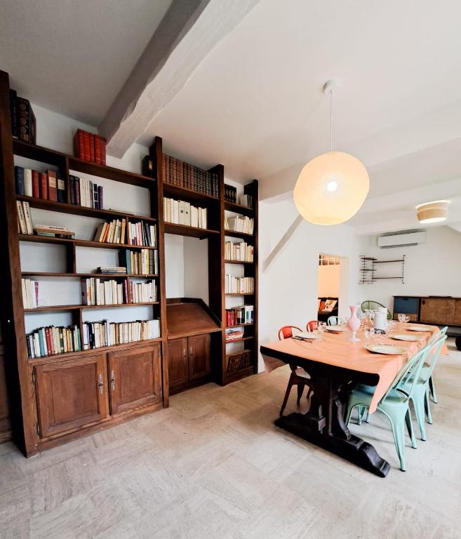 a dining room with a wooden table and bookshelves at Nonni, Maison Familiale - Royan in Royan