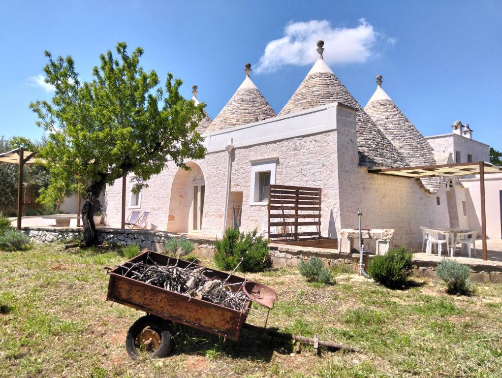 a house with a wheelbarrow in front of it at Trulli Antica chianca in Cisternino