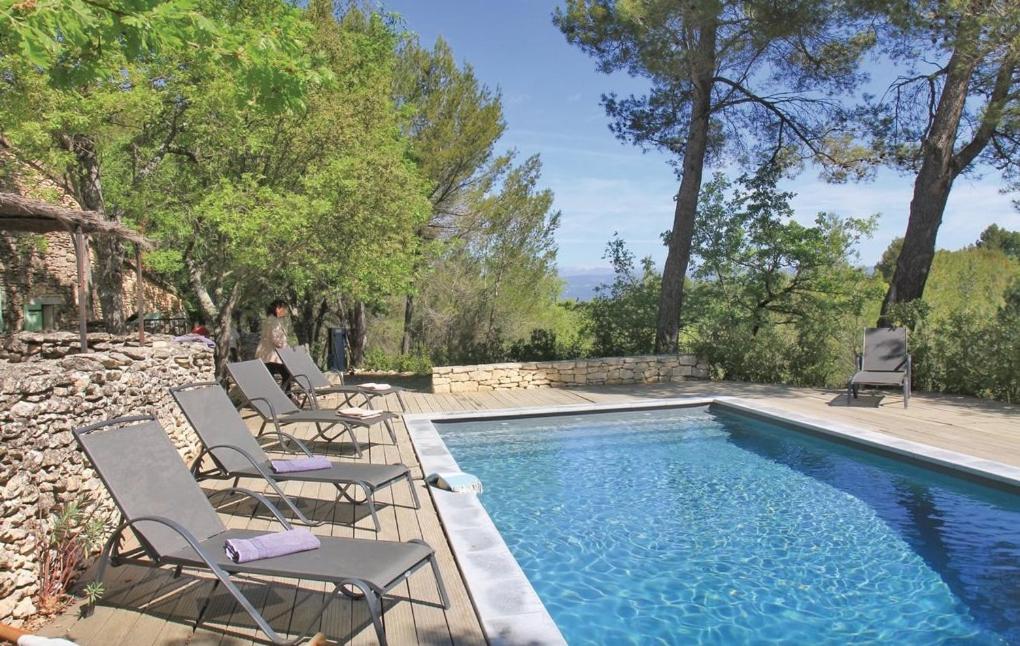 un groupe de chaises assises à côté d'une piscine dans l'établissement Authentique Bergerie Coeur Luberon, à Lacoste