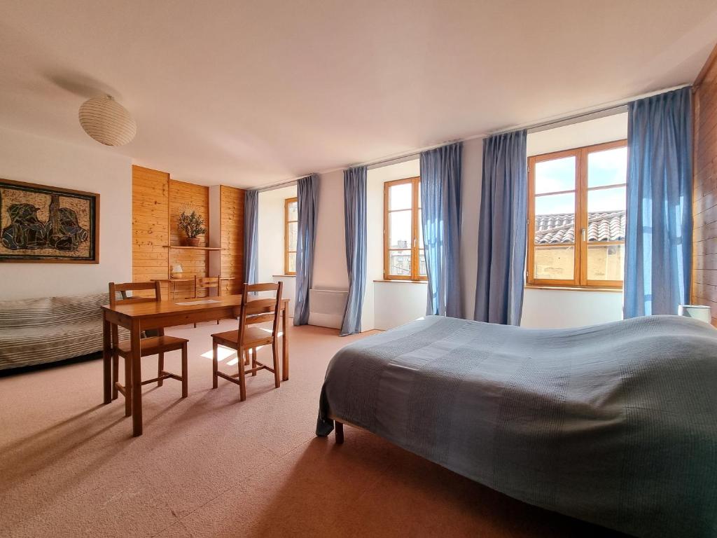 a bedroom with a bed and a desk and a table at Le Clos de l'Âtre - Chambres d'hôtes in La Chaise-Dieu