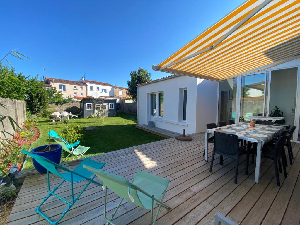 une terrasse en bois avec une table et des chaises dessus dans l'établissement Villa Les Lauriers, à Les Sables-dʼOlonne