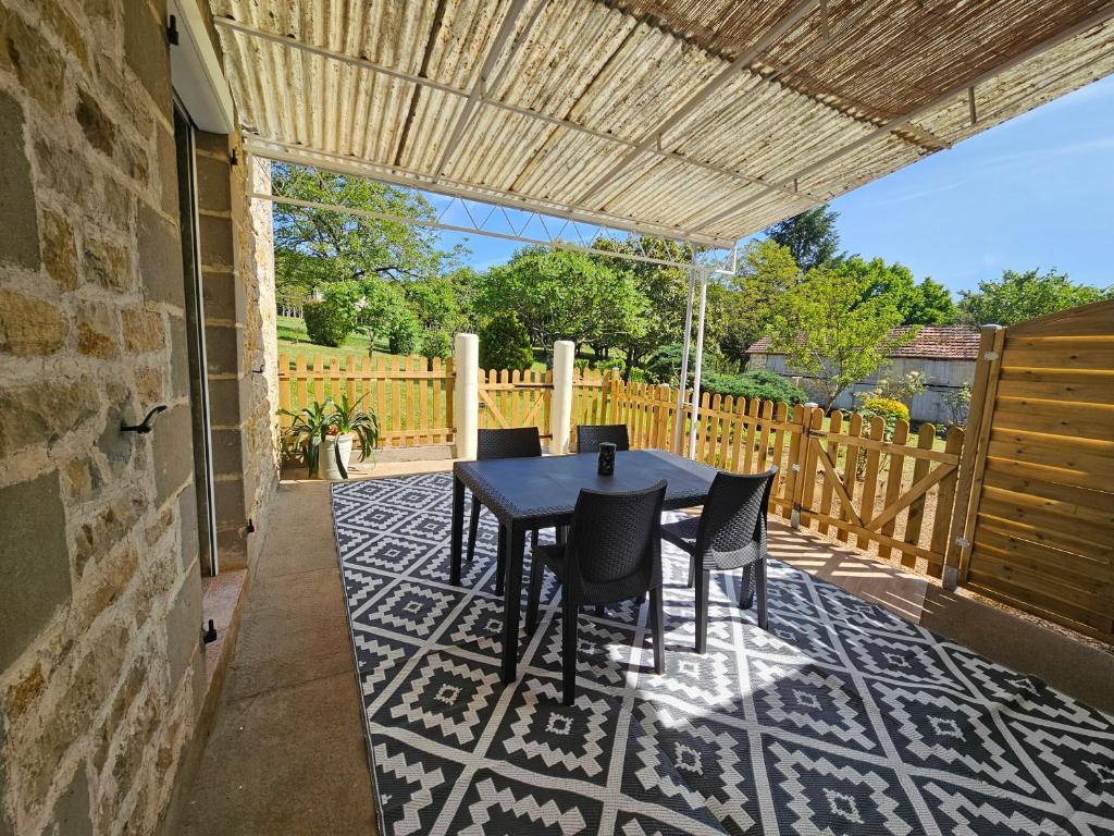 un patio avec une table et des chaises et une clôture dans l'établissement gîte au calme, à Les Coteaux Périgourdins
