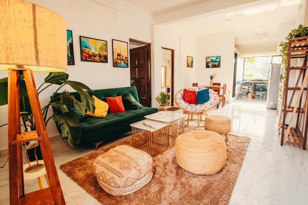 un salon avec un canapé vert et une table dans l'établissement Riverfront 2 Bedroom cozy Apartment by Greenspace, à Siolim