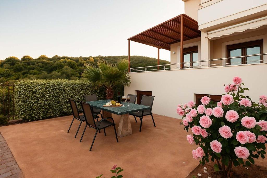 a patio with a table and chairs and pink flowers at Villa Armonia - Beachfront Majestic Retreat in Petalidhion