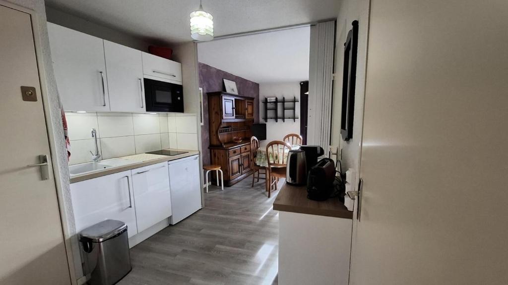 - une cuisine avec des placards blancs, un évier et une table dans l'établissement Résidence Skival - APPARTEMENT 2 PIECES ALPE D'HUEZ QUARTIER DE L'ECLOSE MAE-3421, à Huez