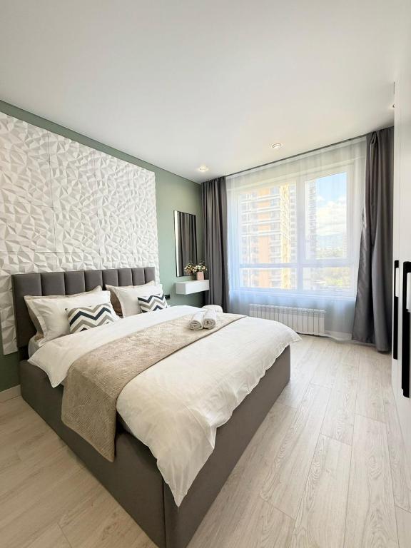 a bedroom with a large bed and a large window at Двухкомнатная квартира с дизайнерским интерьером и видом на горы in Almaty