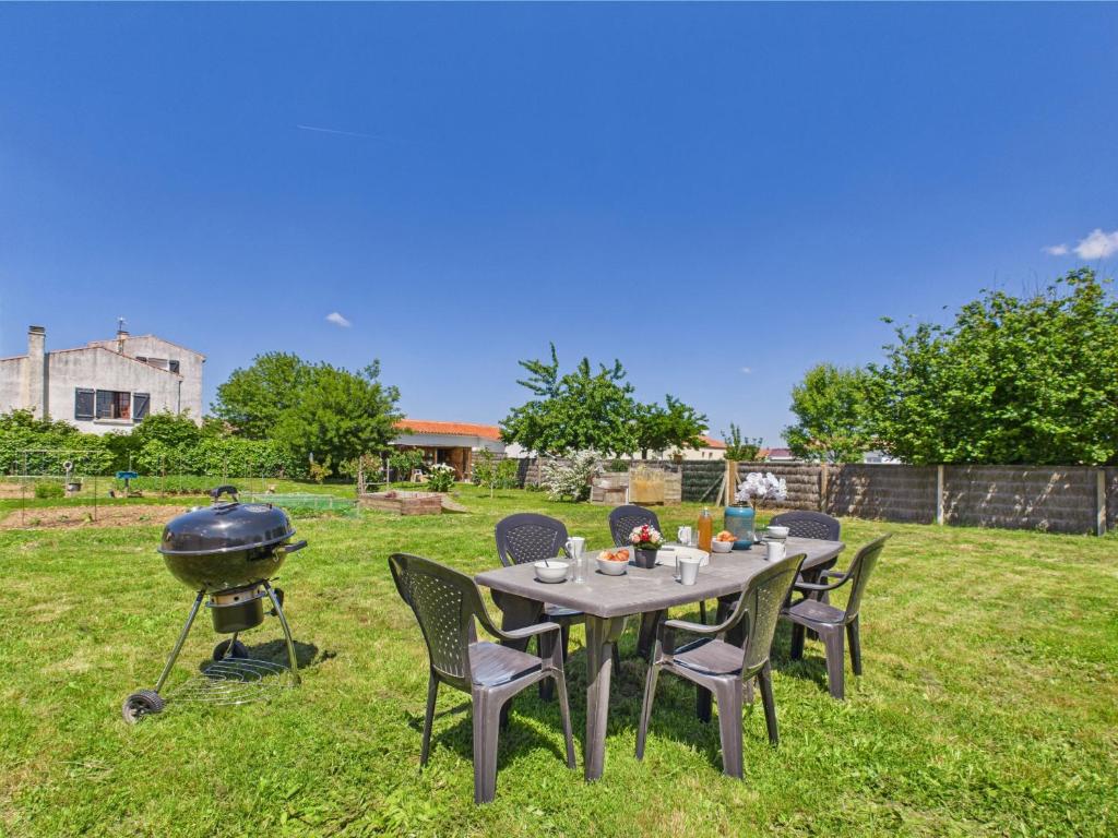 - une table avec des chaises et un grill dans la cour dans l'établissement Jard-sur-Mer - Tranquillité assurée, à Jard-sur-Mer