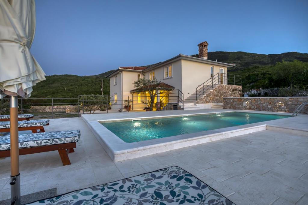 a swimming pool on a patio with a house at VILLA PRISUNAC - private luxury with amazing sea view between Istria and Kvarner in Zagorje