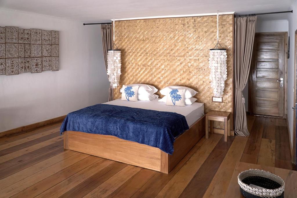 a bedroom with a bed with blue and white pillows at Twin Palms Villa and Homestay in Tuapejat