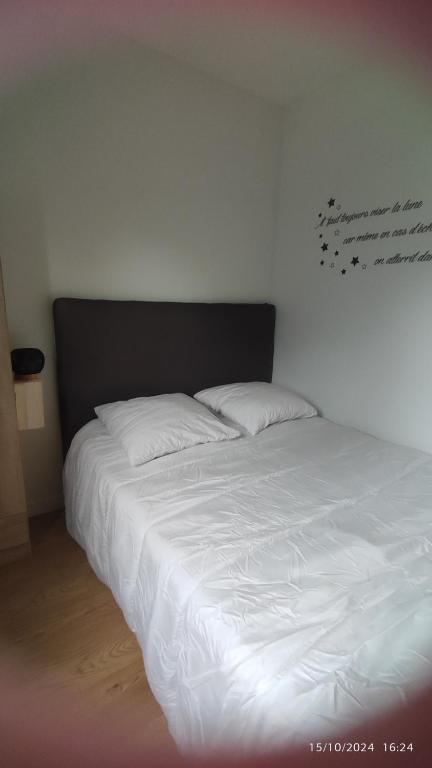 - un lit avec des draps blancs et une tête de lit noire dans l'établissement Studio Smarty, à Parigné-lʼÉvêque